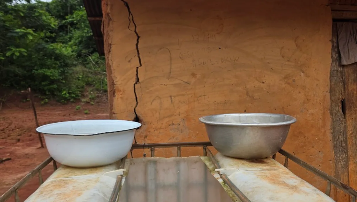 Metal basins of water set on a table outside a clay house