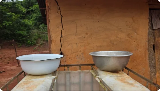 Metal basins of water set on a table outside a clay house