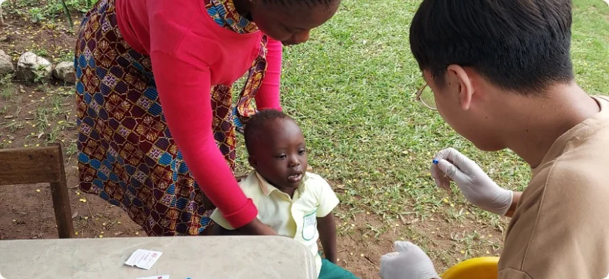 A volunteer giving a health check to a young child held by her mother